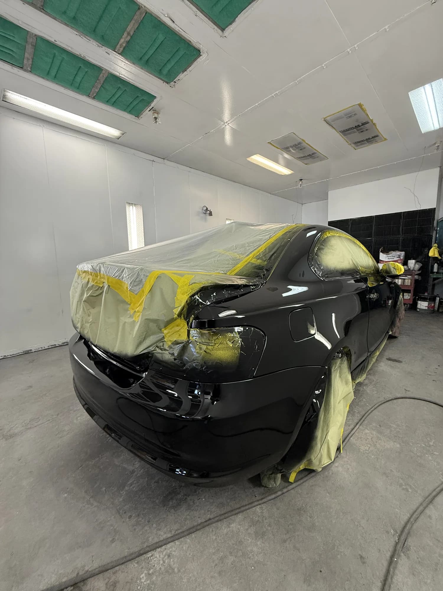 Car masked and prepped for refinishing inside the Wu's Auto Center paint booth